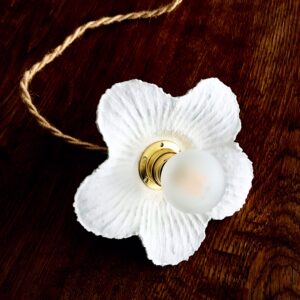 lampe baladeuse fleur blanche striée en papier mâché, avec cordon électrique torsadé en jute naturel, posée sur une table en bois.