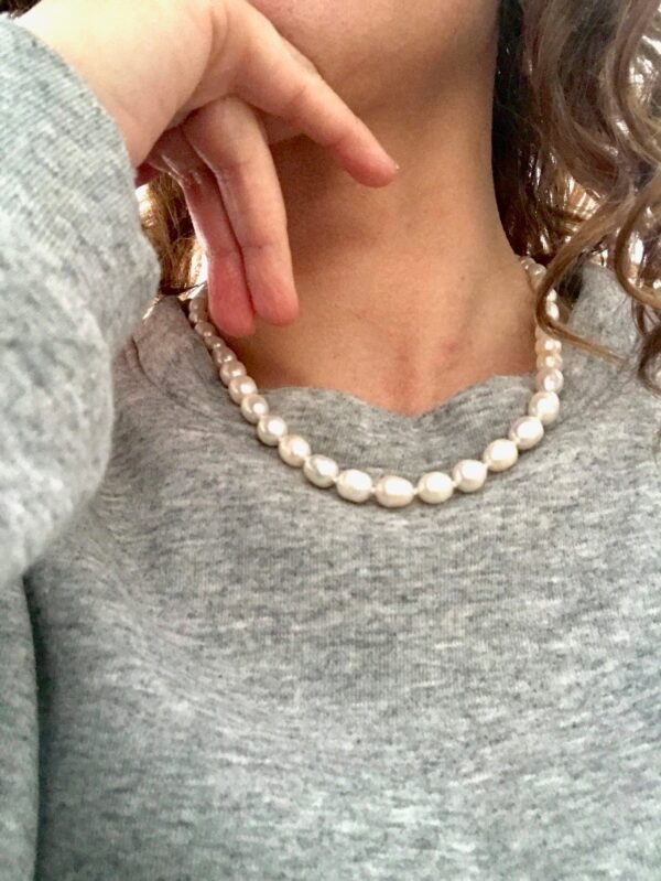 collier de perles d'eau douce blanc nacré, court, porté avec un sweat-shirt gris chiné.
