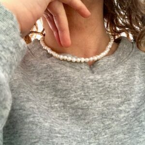 collier court, ras de cou, de petites perles d'eau douce blanc nacré porté avec un sweat-shirt gris chiné.